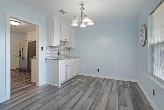 kitchen featuring white cabinets, backsplash, hardwood / wood-style flooring, and stainless steel fridge