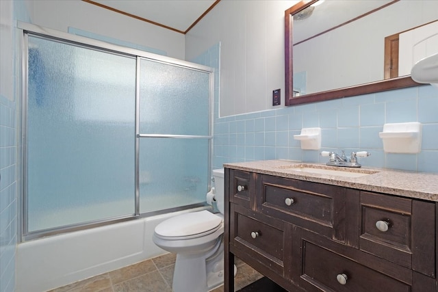 full bathroom with vanity, toilet, combined bath / shower with glass door, tile walls, and tile patterned flooring