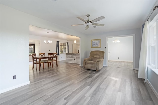 living area with ceiling fan with notable chandelier and light hardwood / wood-style floors