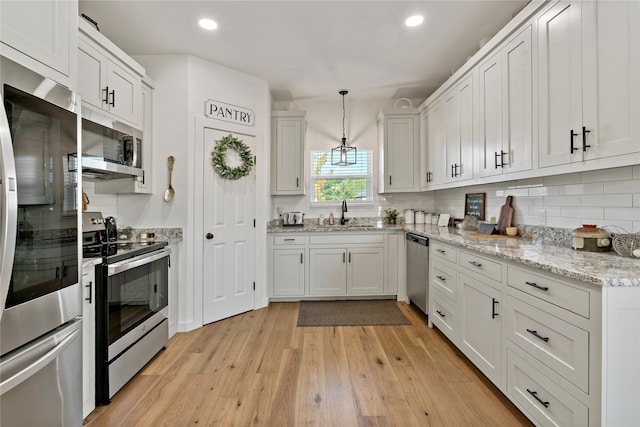 kitchen featuring white cabinetry, stainless steel appliances, light hardwood / wood-style flooring, decorative light fixtures, and sink