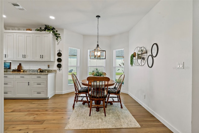 dining room with light hardwood / wood-style flooring and a notable chandelier