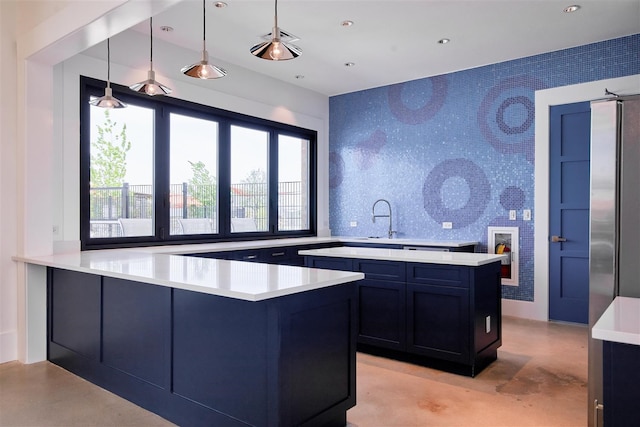 kitchen featuring tasteful backsplash, sink, kitchen peninsula, and decorative light fixtures