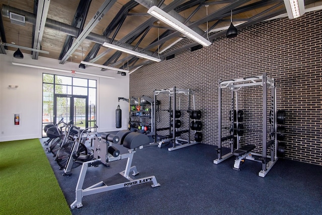 gym featuring brick wall and high vaulted ceiling