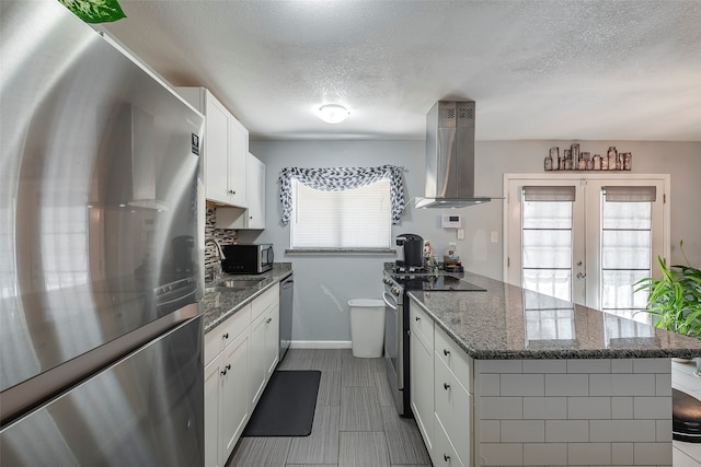 kitchen featuring sink, white cabinets, stainless steel appliances, exhaust hood, and dark stone countertops