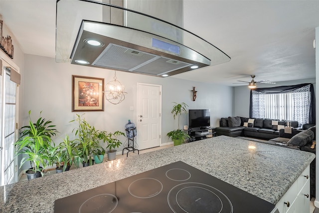 kitchen with ceiling fan with notable chandelier, light stone counters, and plenty of natural light