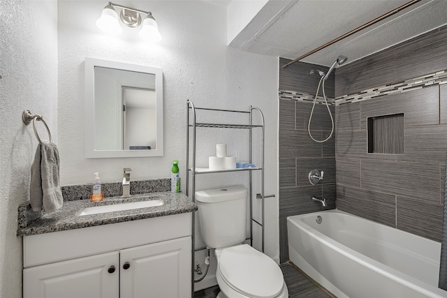 full bathroom with a textured ceiling, tiled shower / bath, vanity, and toilet