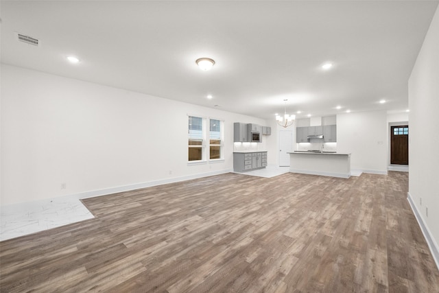 unfurnished living room with a chandelier and wood-type flooring