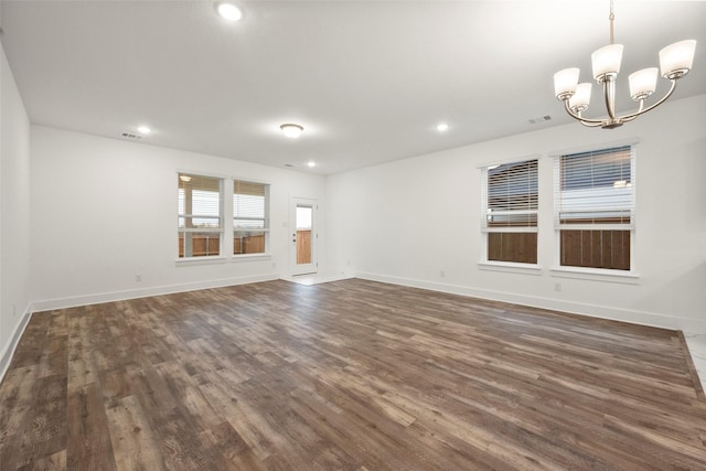 empty room featuring dark wood-type flooring and an inviting chandelier