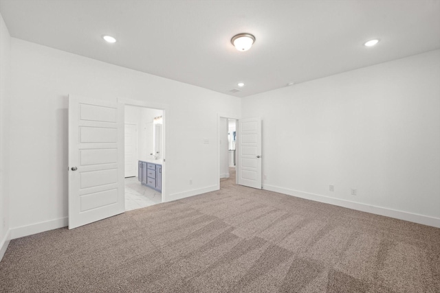 unfurnished bedroom with ensuite bathroom and light colored carpet