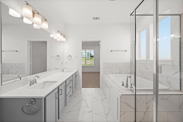 bathroom with vanity and tiled tub