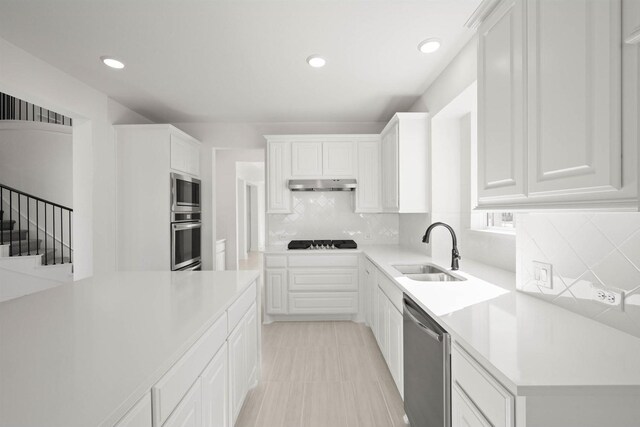 kitchen with tasteful backsplash, appliances with stainless steel finishes, sink, and white cabinets