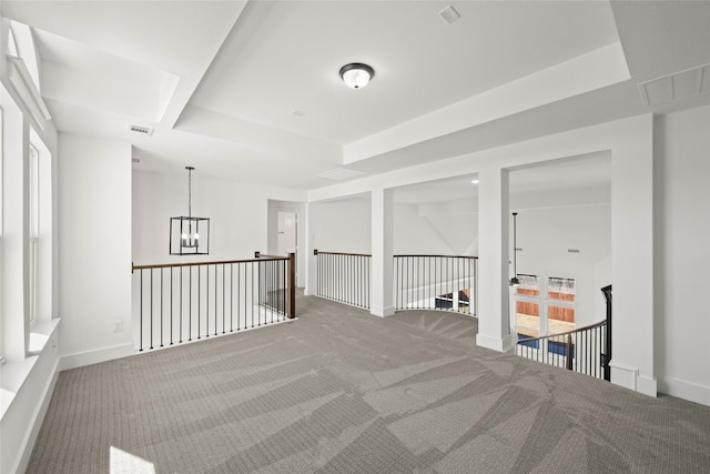 unfurnished room featuring a notable chandelier, a tray ceiling, and carpet floors