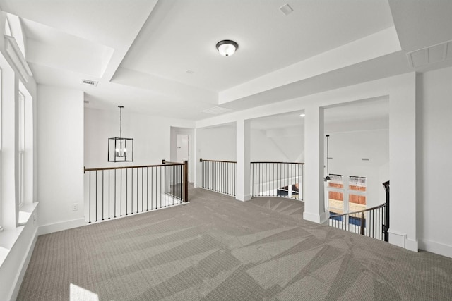 spare room featuring a notable chandelier, a tray ceiling, and carpet floors