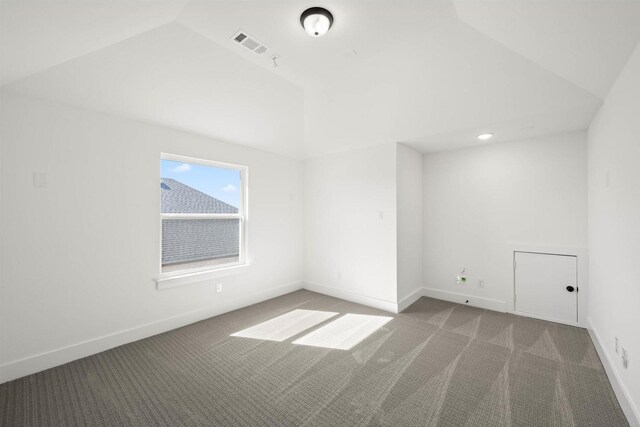 carpeted empty room featuring vaulted ceiling