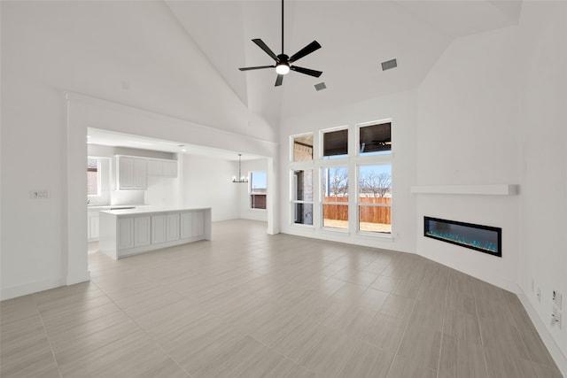 unfurnished living room with high vaulted ceiling and ceiling fan