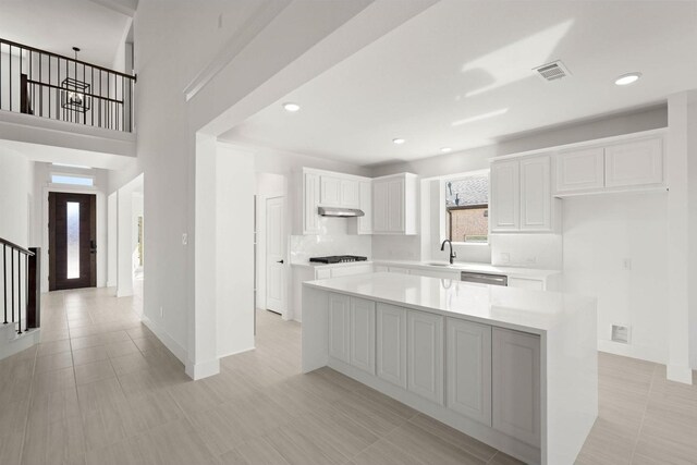 kitchen with sink, white cabinetry, dishwasher, a kitchen island, and black gas cooktop