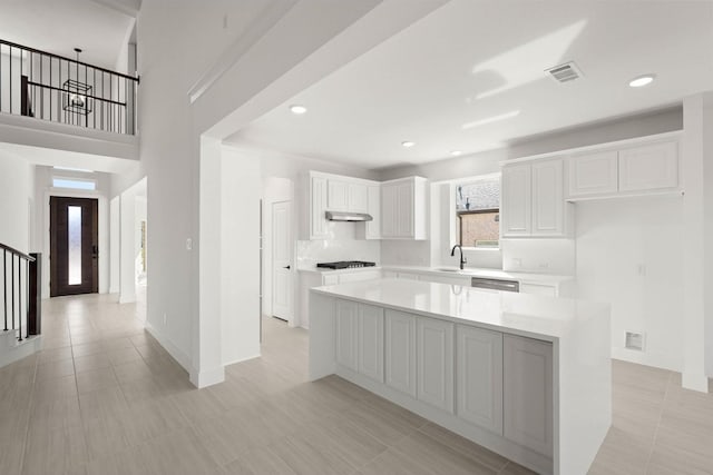 kitchen with dishwasher, sink, white cabinets, a center island, and black gas stovetop