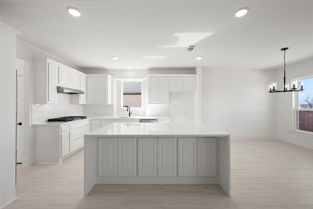 kitchen featuring sink, stainless steel gas stovetop, white cabinets, and a kitchen island