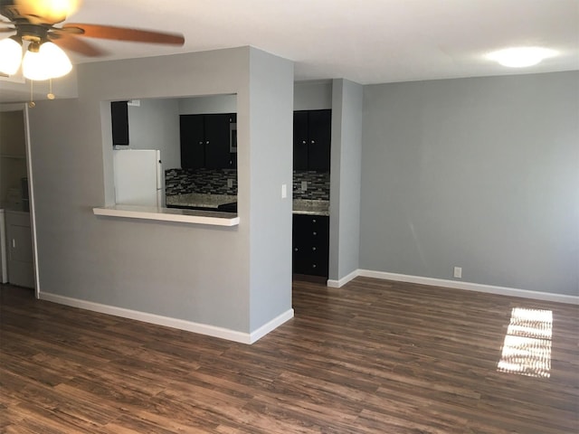 interior space featuring backsplash, ceiling fan, white fridge, and dark hardwood / wood-style flooring