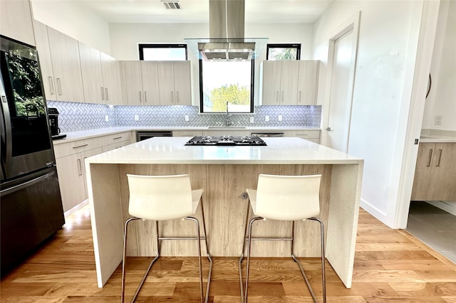 kitchen featuring a kitchen breakfast bar, a center island, black fridge, and a wealth of natural light