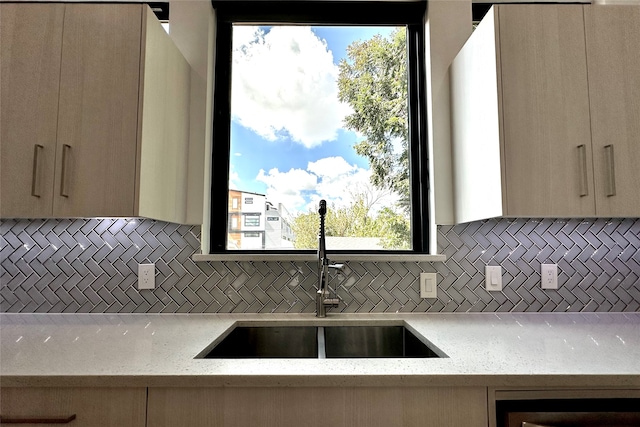 kitchen featuring light stone counters, light brown cabinetry, and sink