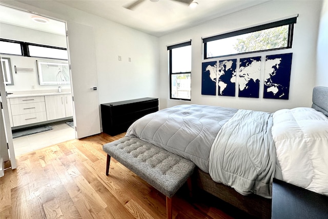 bedroom featuring ceiling fan, light wood-type flooring, and ensuite bath