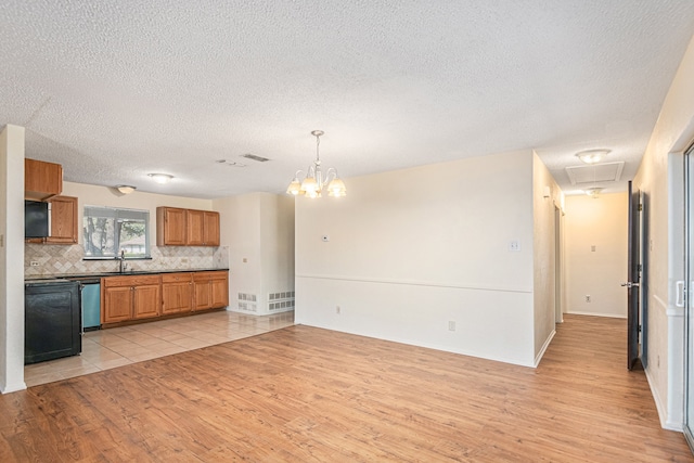 kitchen with pendant lighting, a textured ceiling, sink, light hardwood / wood-style flooring, and an inviting chandelier