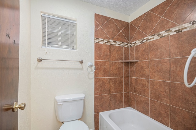 bathroom featuring a textured ceiling, tiled shower / bath, and toilet