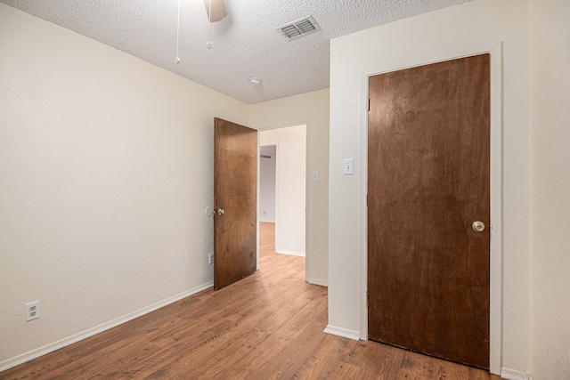 unfurnished bedroom with a textured ceiling, ceiling fan, a closet, and light hardwood / wood-style flooring