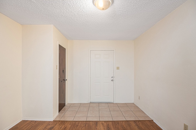 empty room with light hardwood / wood-style floors and a textured ceiling