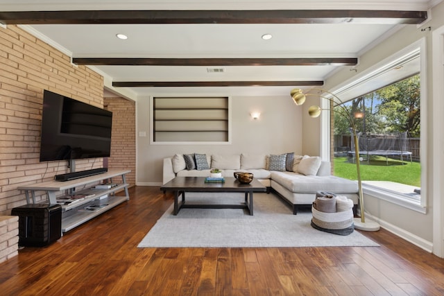 living room featuring beam ceiling, dark wood-type flooring, and brick wall