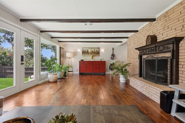 living room featuring beamed ceiling, dark wood-type flooring, and a brick fireplace