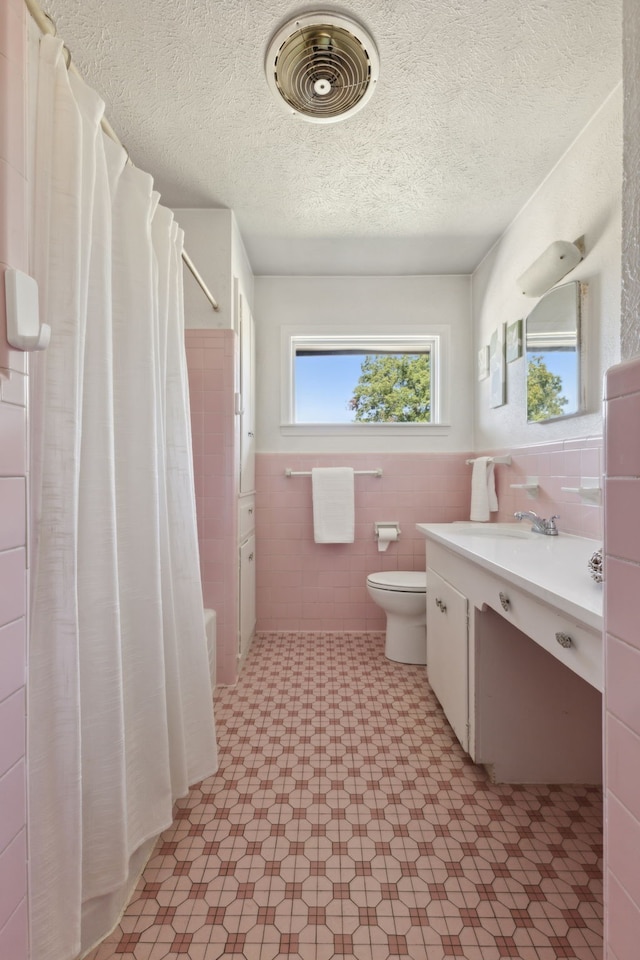 full bathroom with sink, toilet, shower / bathtub combination with curtain, tile walls, and a textured ceiling