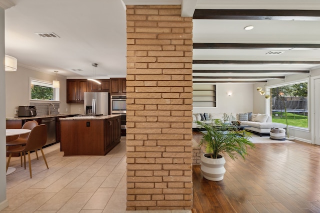 kitchen featuring beamed ceiling, a kitchen island, stainless steel appliances, and decorative light fixtures