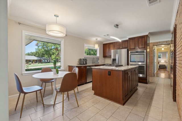 kitchen with a center island, hanging light fixtures, brick wall, crown molding, and appliances with stainless steel finishes