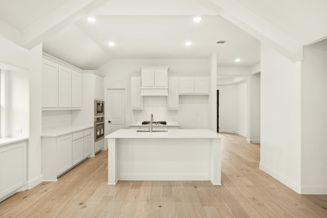 kitchen featuring white cabinetry, stainless steel oven, and an island with sink