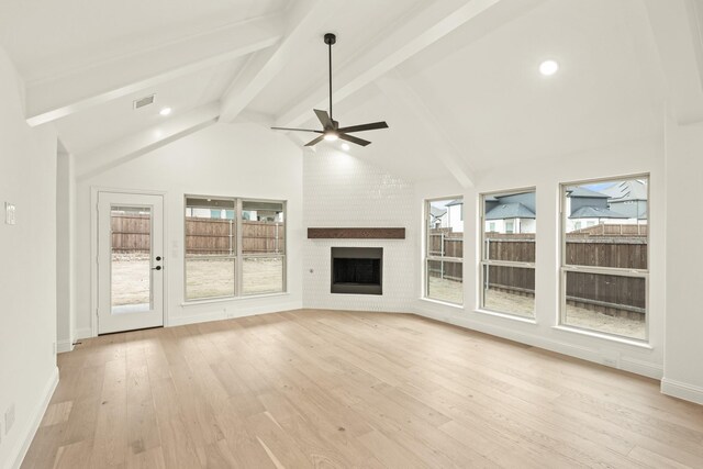 unfurnished living room with high vaulted ceiling, beamed ceiling, ceiling fan, a brick fireplace, and light hardwood / wood-style flooring