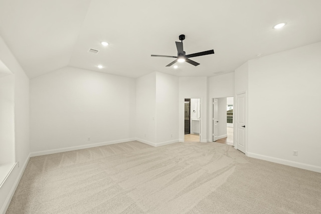 empty room with ceiling fan, vaulted ceiling, and light carpet