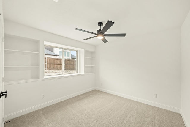 carpeted empty room featuring ceiling fan and built in features