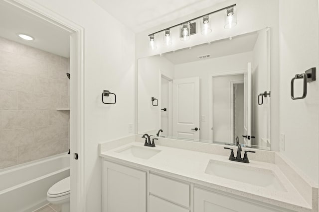 full bathroom featuring vanity, tiled shower / bath, and toilet