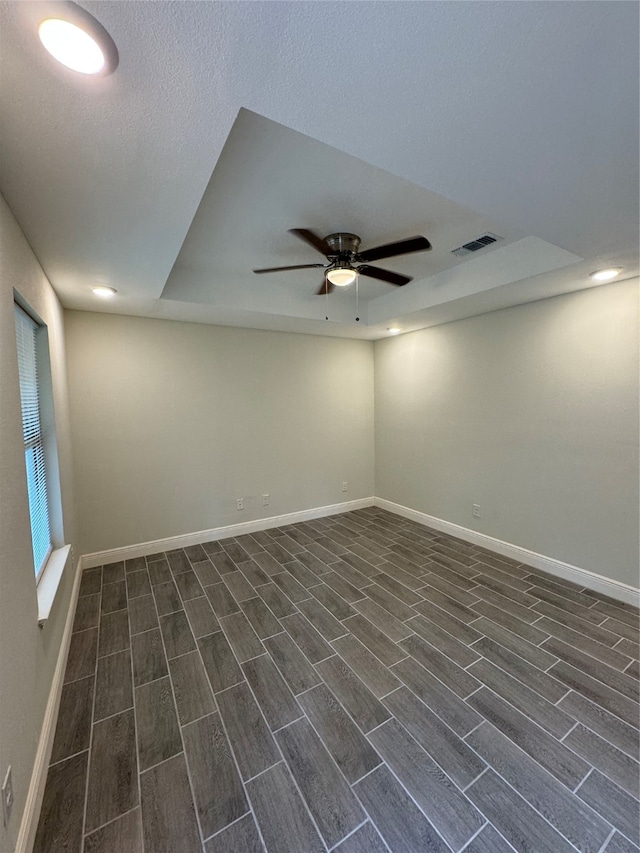 spare room with a raised ceiling, dark hardwood / wood-style floors, and ceiling fan