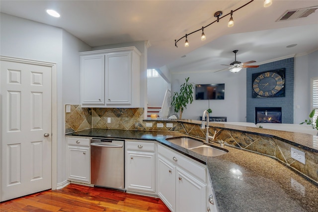 kitchen featuring sink, stainless steel dishwasher, wood-type flooring, a brick fireplace, and white cabinetry