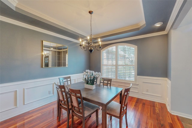 dining room with a notable chandelier, a tray ceiling, crown molding, and hardwood / wood-style flooring