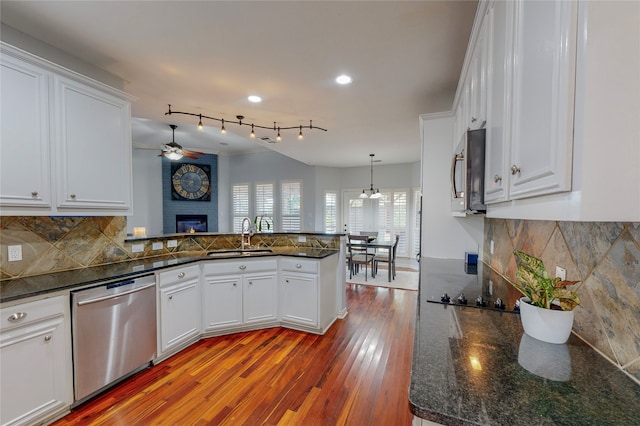 kitchen with appliances with stainless steel finishes, white cabinetry, a fireplace, light hardwood / wood-style flooring, and sink