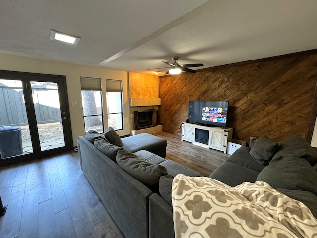 living room with a fireplace, wood walls, dark hardwood / wood-style floors, and ceiling fan