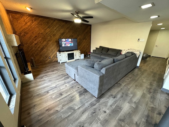 living room featuring ceiling fan, hardwood / wood-style flooring, and wooden walls