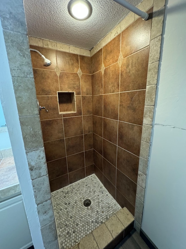 bathroom featuring a textured ceiling and tiled shower