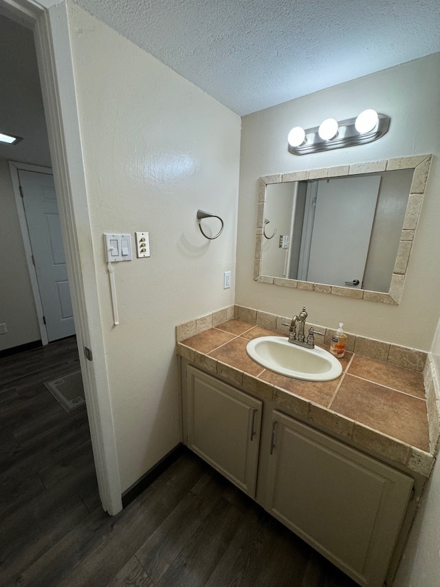 bathroom with a textured ceiling, wood-type flooring, and vanity