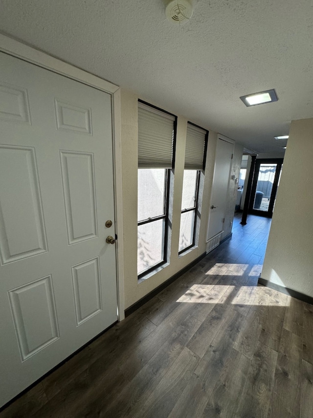 corridor featuring a textured ceiling and dark hardwood / wood-style floors