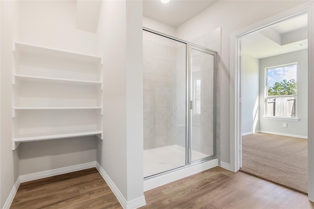 bathroom with hardwood / wood-style flooring and a shower with shower door